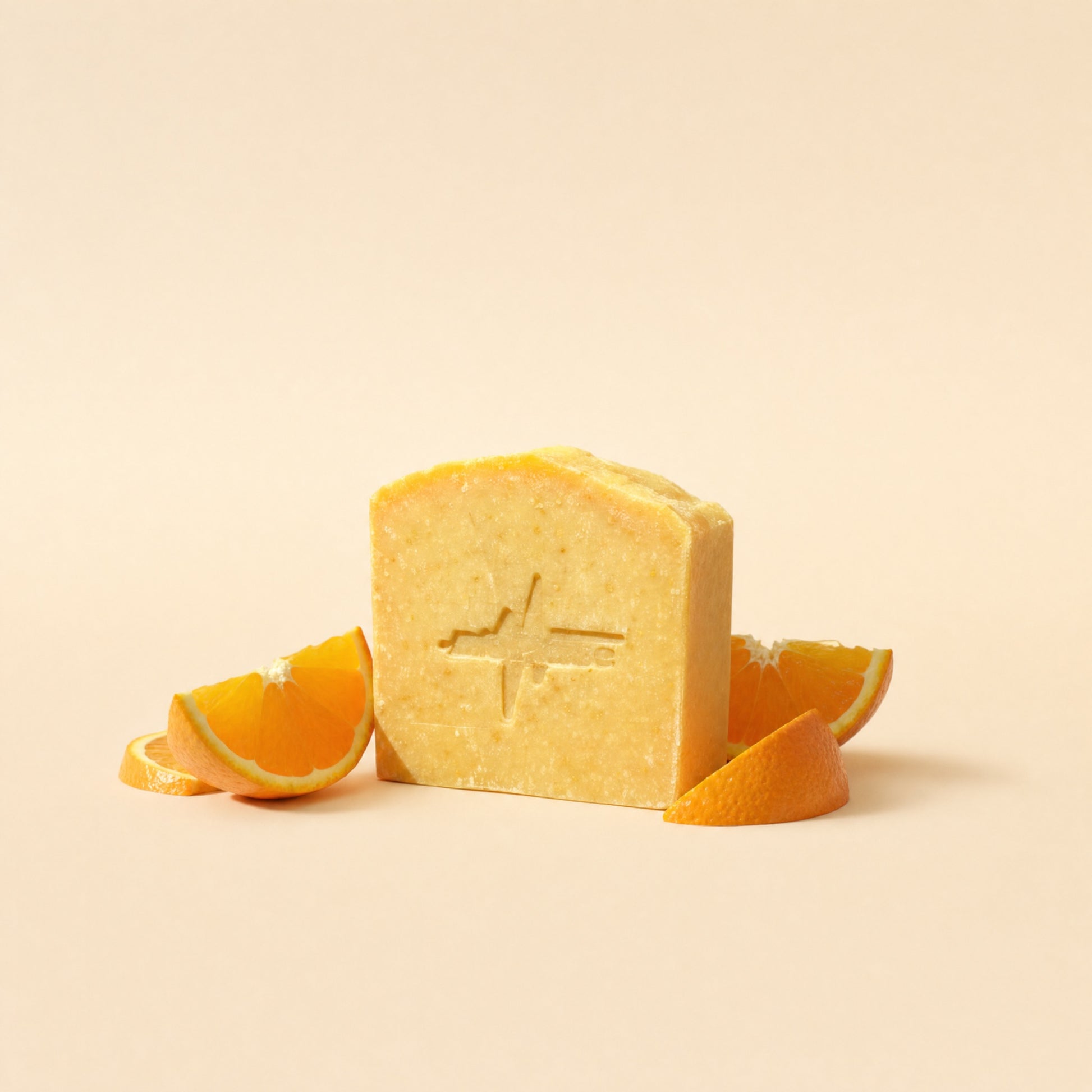 BioPulse Organic Tallow Soap orange bar with the pulse logo stamp, beside fresh orange slices