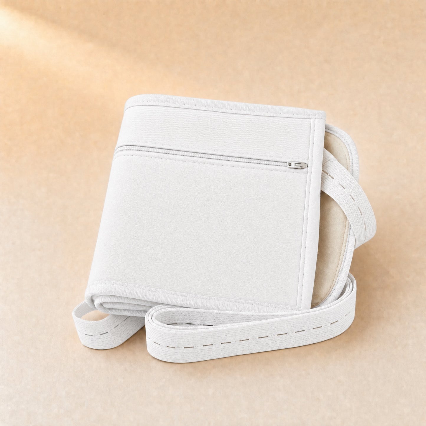 Folded white organic cotton castor oil waist wrap with a zip pocket and elastic straps