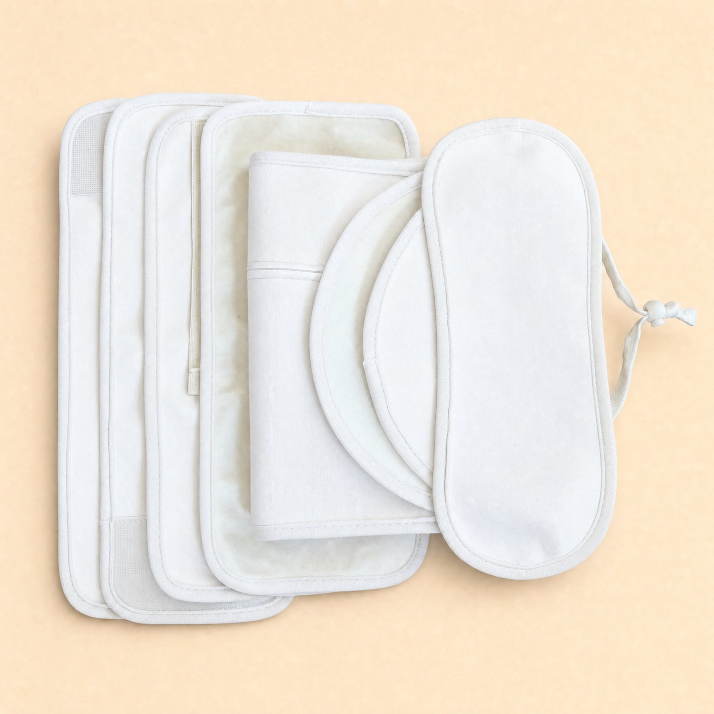 White organic cotton castor oil wraps in assorted shapes, including a round pad and an eye mask with ties